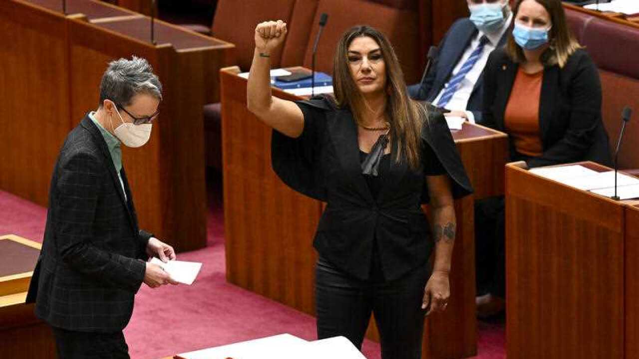 lidia thorpe in the senate chamber with her fist raised.