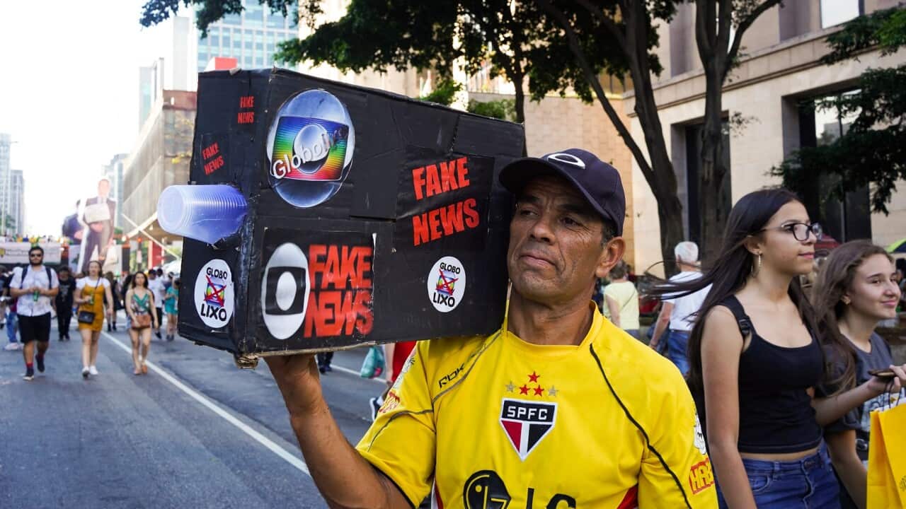 A demonstrator holds up a box that mimics a TV news camera