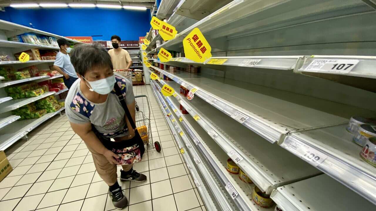 A woman checks an almost empty shelf as residents rushed to buy grocery essentials inside a supermarket in Taipei, Taiwan, 17 May 2021.