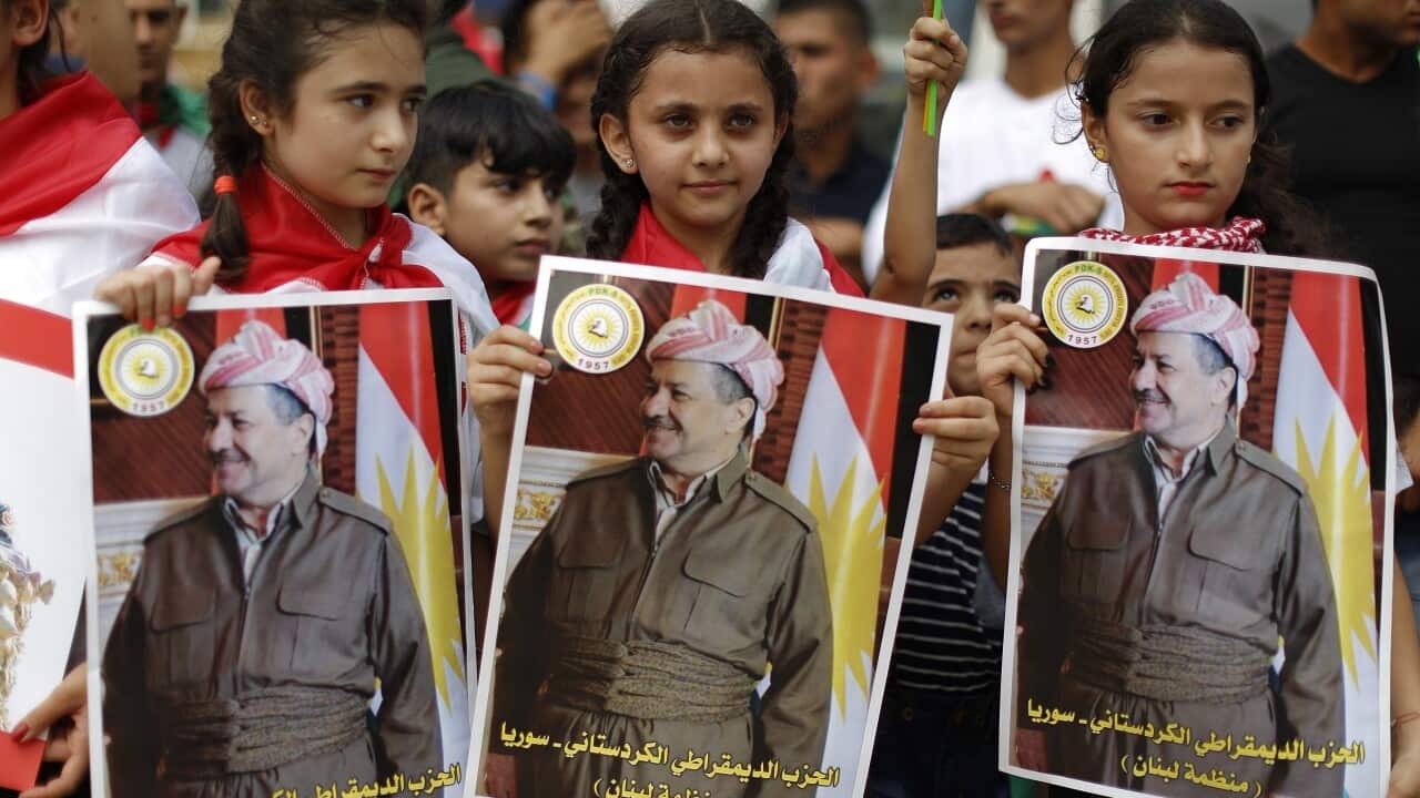 Kurdish girls hold posters showing Iraqi Kurdish leader Masoud Barzani