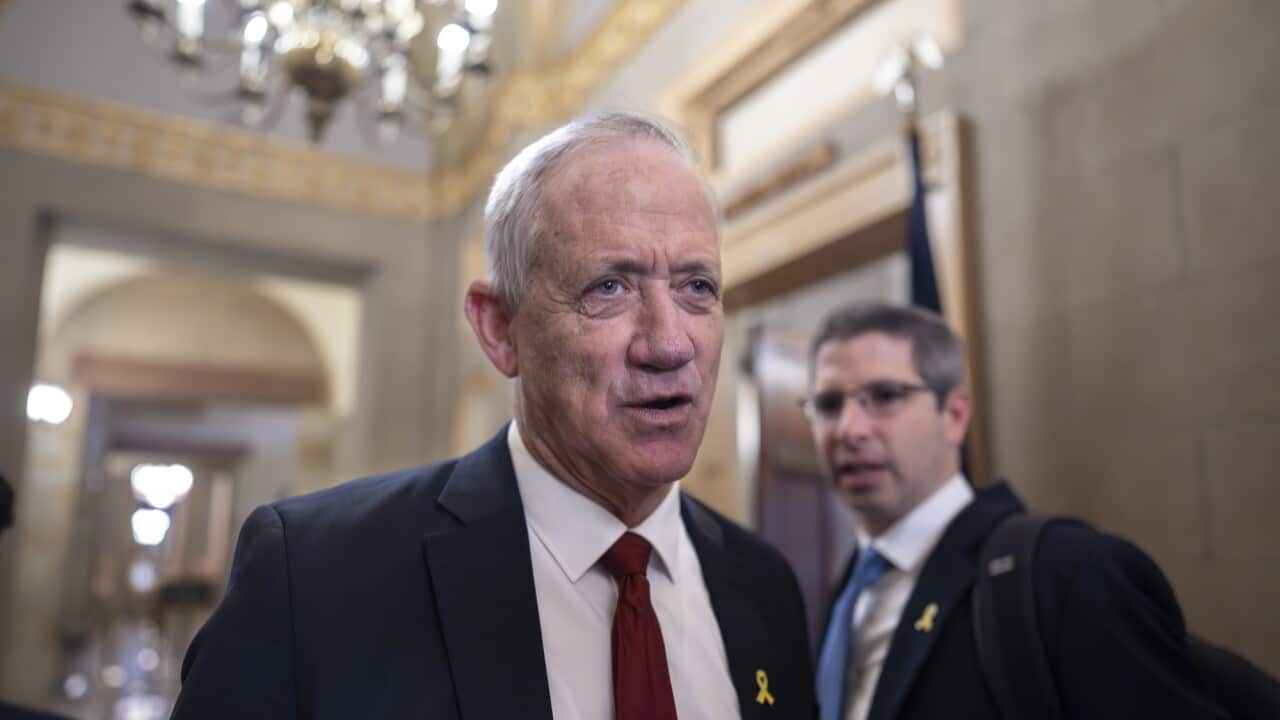 A man in a suit and tie speaking in a hallway.