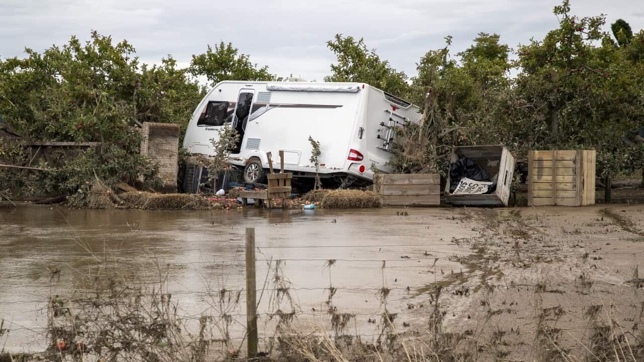 A recreation vehicle is piled on debris and surrounded by floodwater in Hawkes Bay