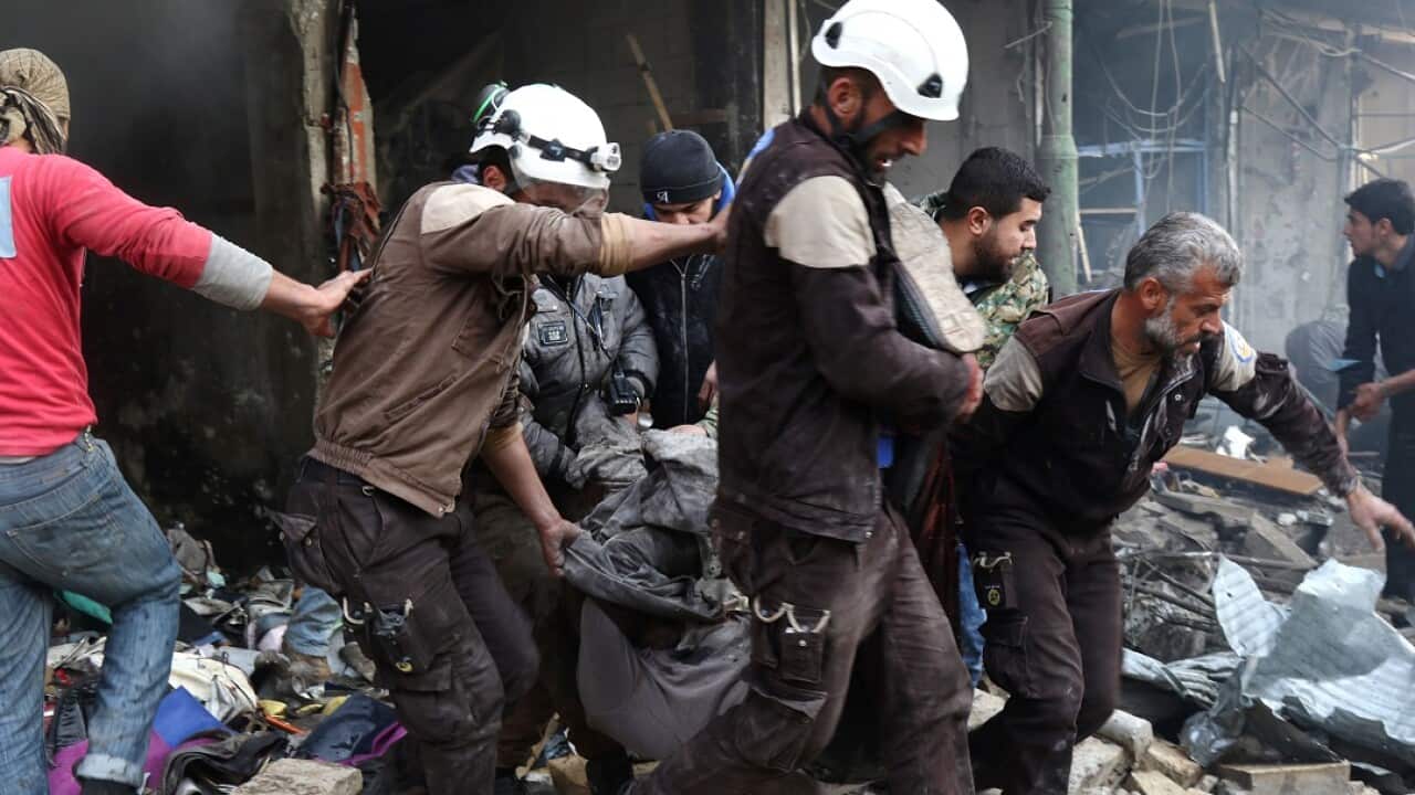 Members of the White Helmets evacuate a victim from a building following an air strike.