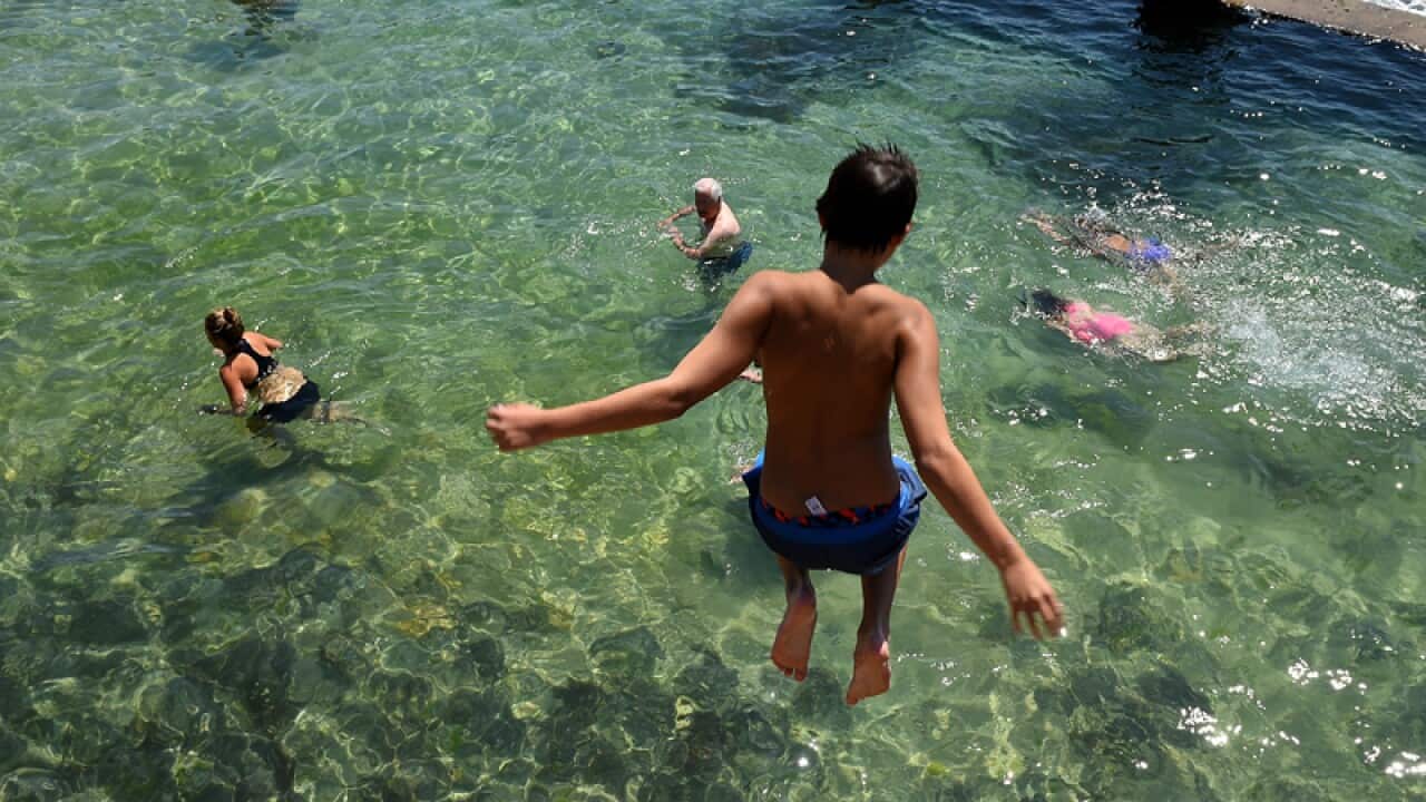 A boy is seen jumping into the ocean pool at Coogee beach