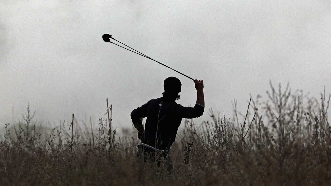 A Palestinian protester throws stones at Israeli troops during clashes near the border with Israel.
