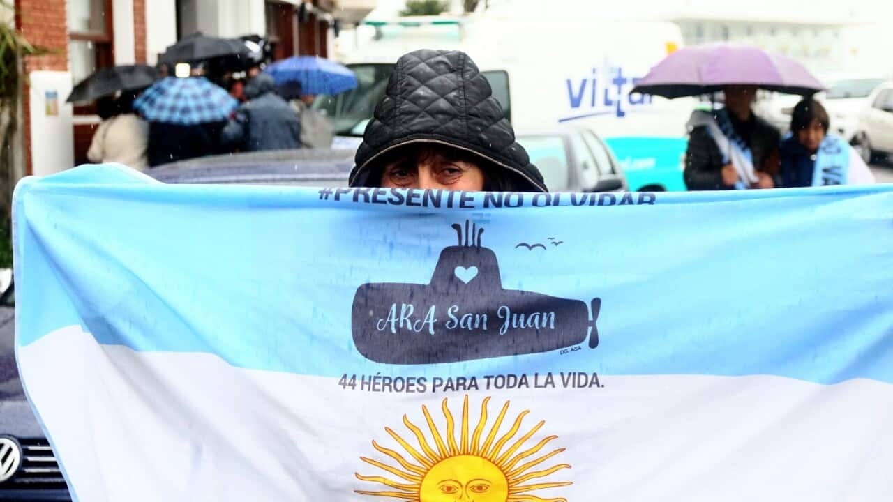 A relative of a crew member of the Ara San Juan holds an Argentinian flag with the words '44 heroes for life'.