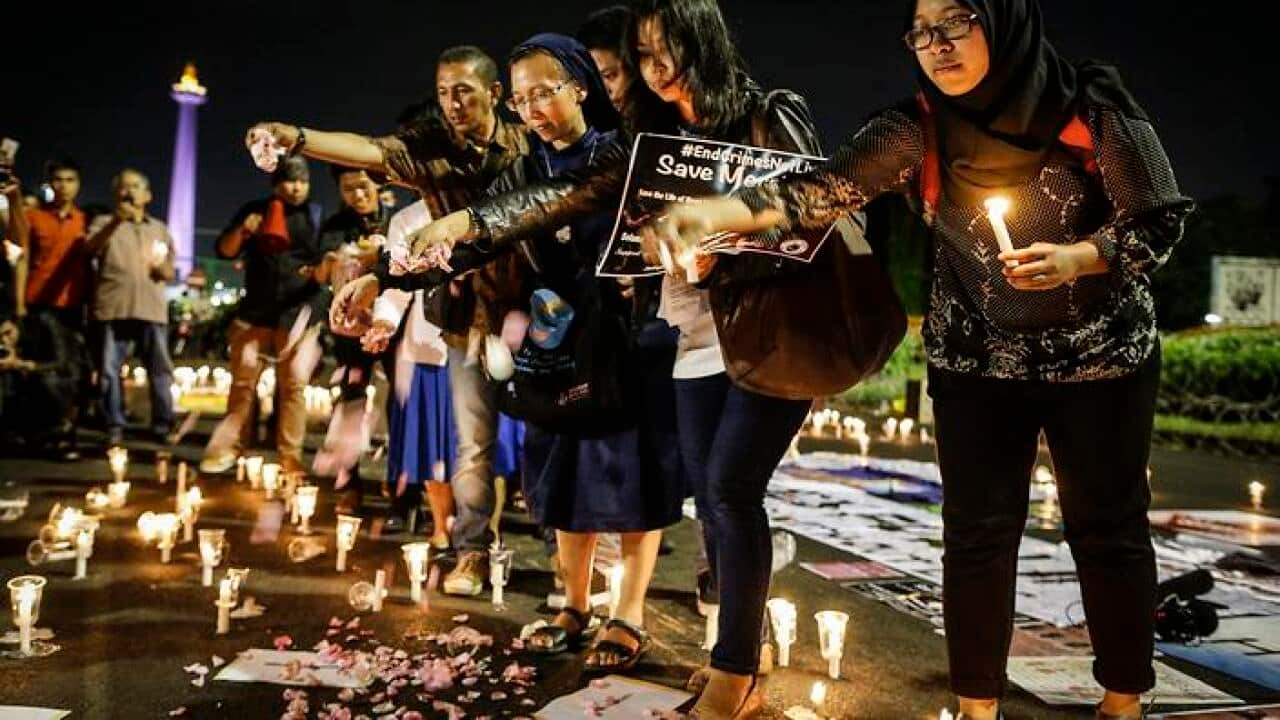 epa05445414 Indonesian activists throw flower petals during a candlelight protest against death penalty executions, outside the presidential palace in Jakarta, Indonesia, 28 July 2016. According to media reports, Indonesian government is expected to exec