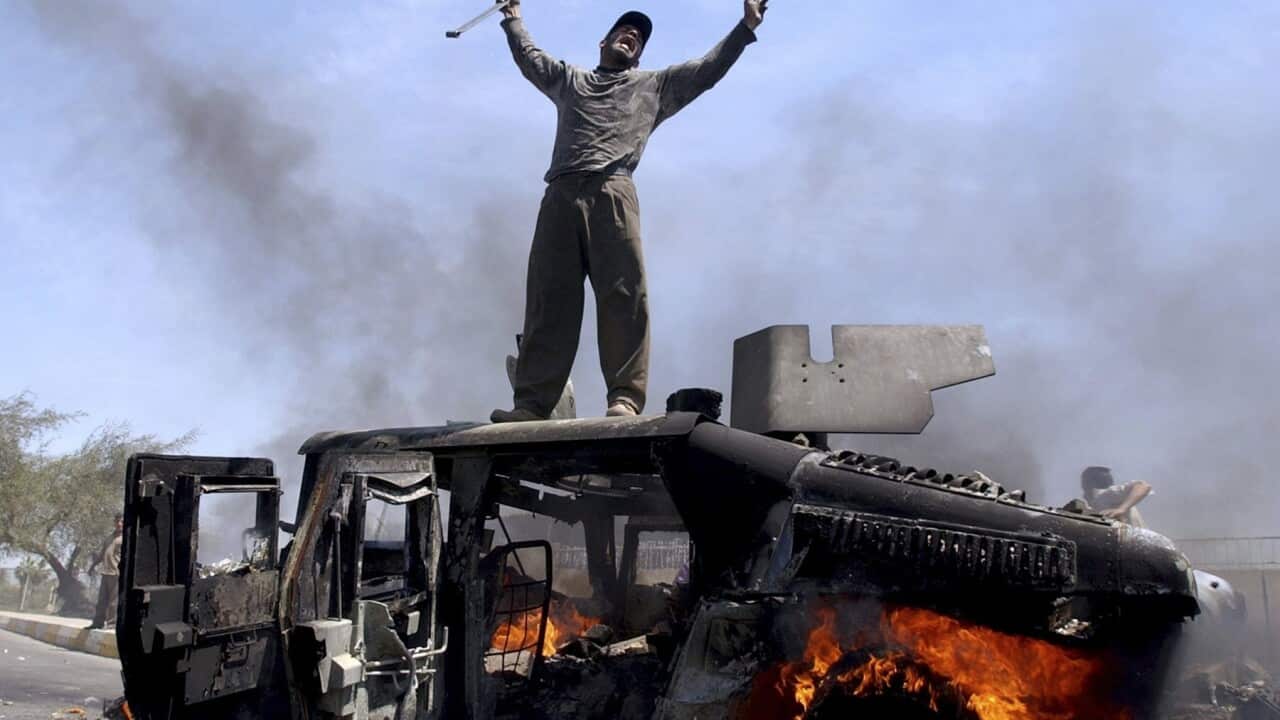 An Iraqi man on top of a burning army vehicle in 2004