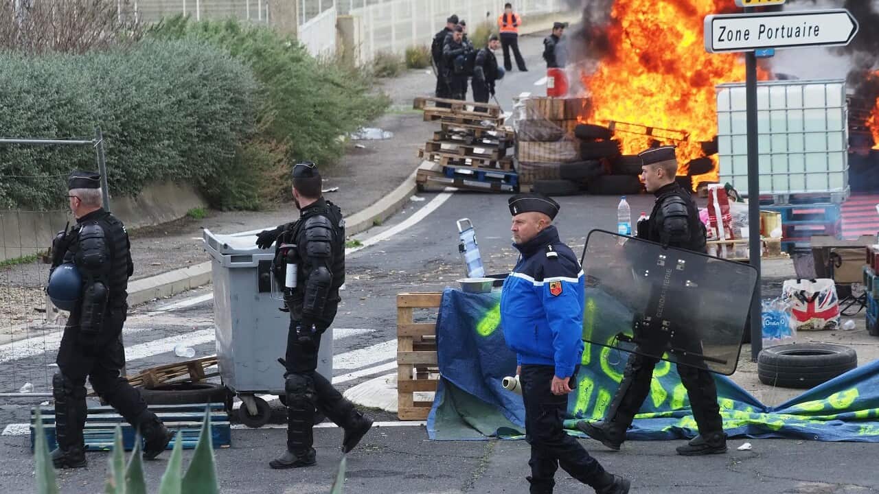Gendarmes walk at a burning barricade as they disperse Yellow Vest protesters blocking a fuel depot.