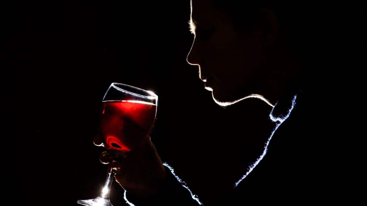 A woman drinking a glass of red wine