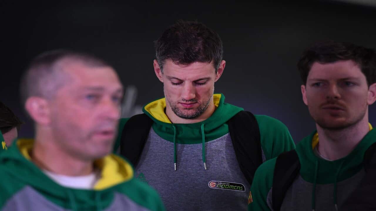 Daniel Kickert of the Boomers (centre), the Australian national basketball team, listens to coach Andrej Lemanis (left) on arrival at Brisbane airport.