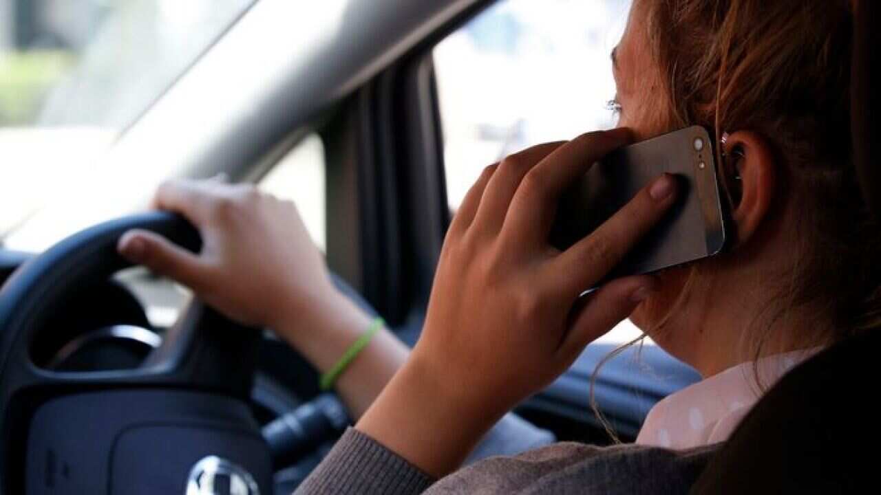 photo of a woman talking on her phone while driving, as a new survey suggests that young drivers are most likely to talk on the phone while driving..