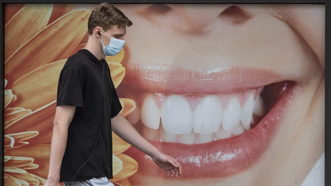 A young man walks past a dental office in Vancouver