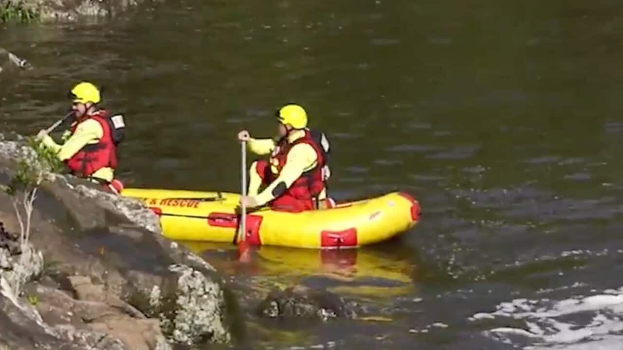 Two rescuers rowing a rescue canoe on a river.