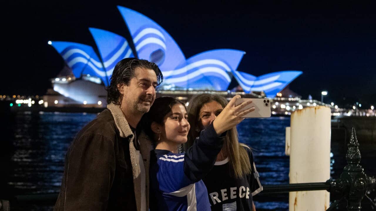 selfie in front of Sydney Opera House bathed in the colours of the Greek flag