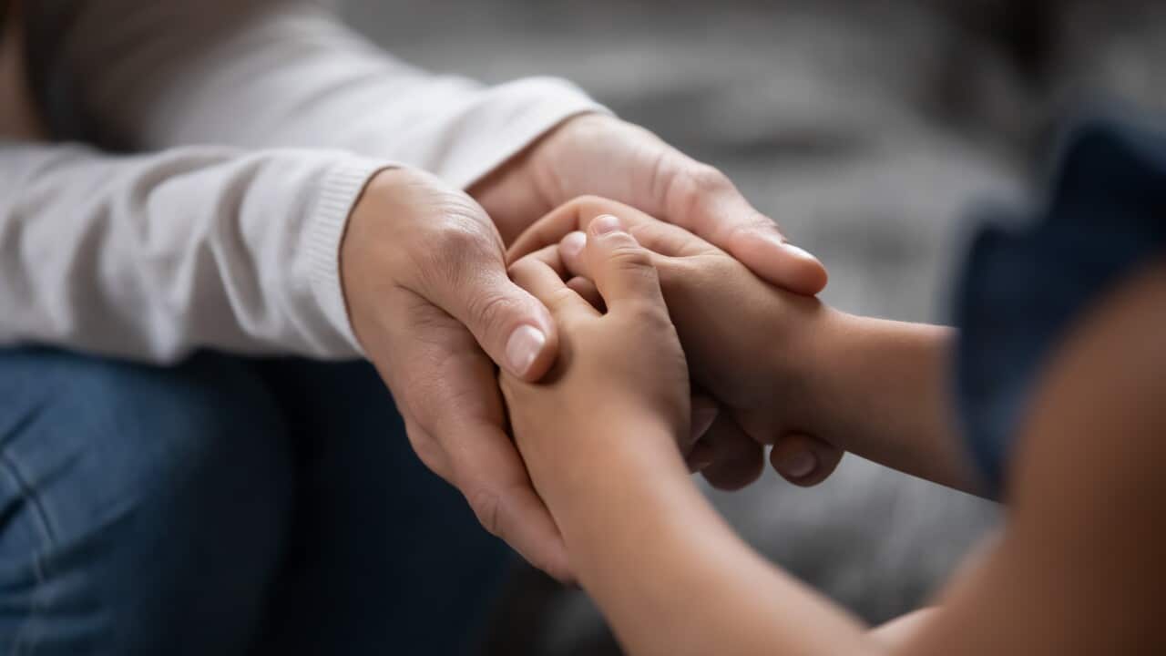 An adult holding a child's hands.