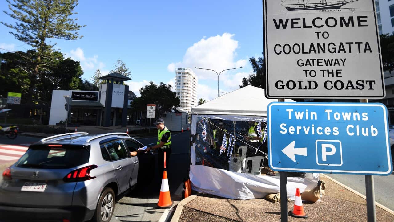 A police officer inspects a car at a check point on the Queensland-New South Wales border in Coolangatta on the Gold Coast.