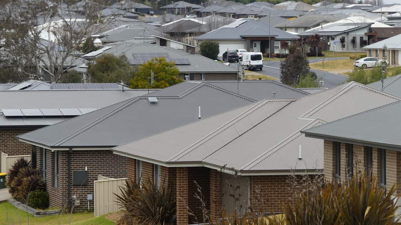 A row of houses with grey roofs in a suburban street.