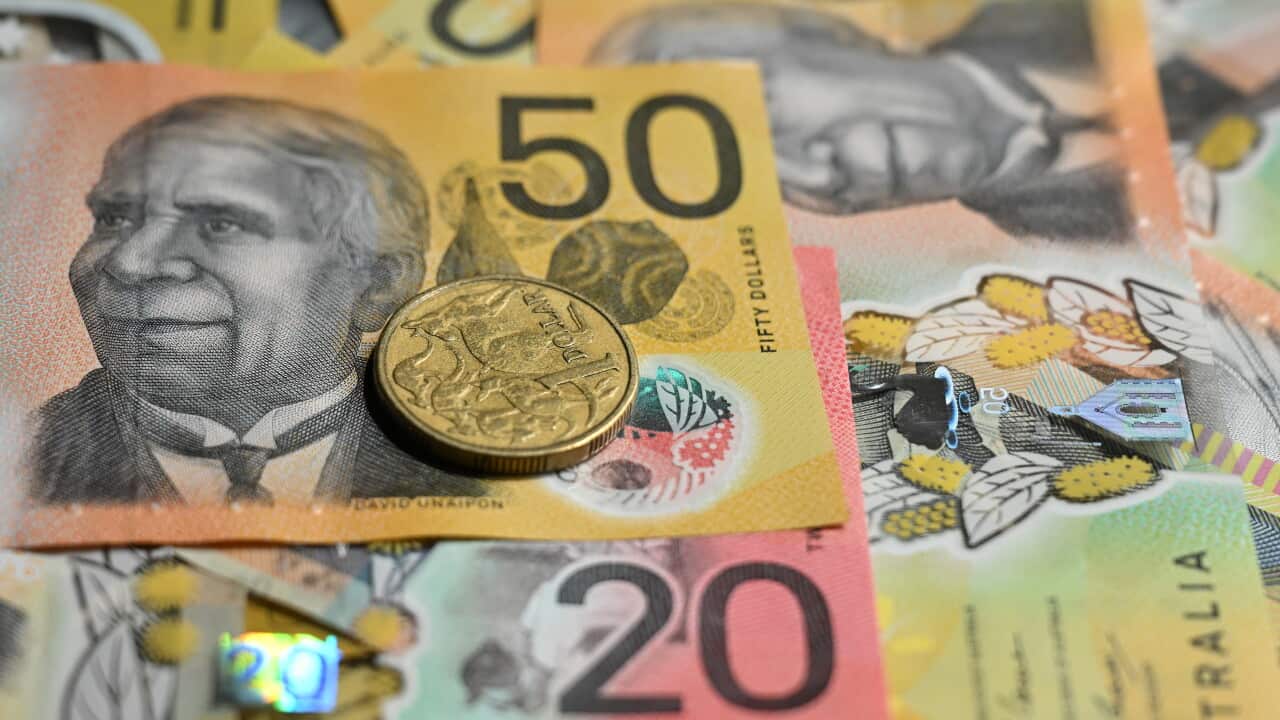 A $50 note and a $20 note are seen prominently among other Australian dollar notes, with a $1 coin sitting on top of them.