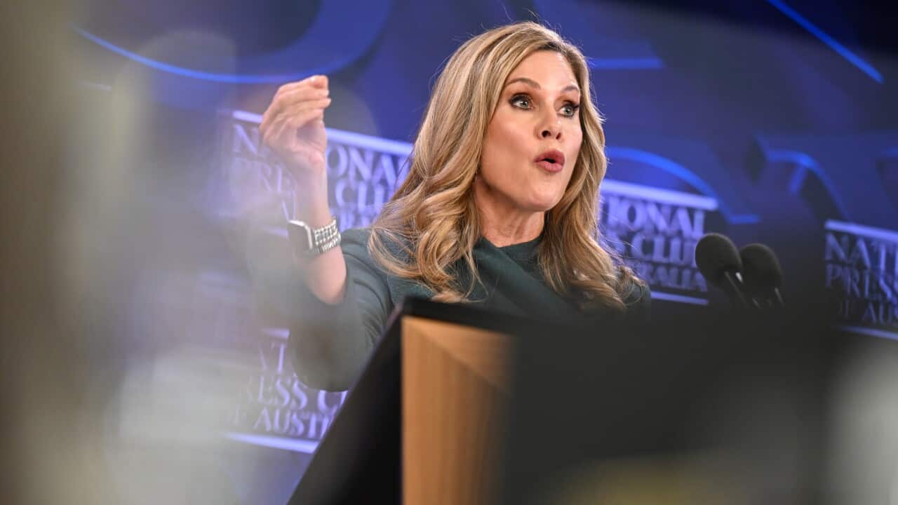 Julie Inman Grant stands behind a podium in front of a National Press Club backdrop.