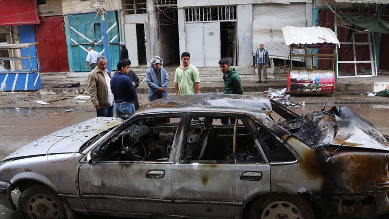 People inspect the site of a car bomb explosion in Baghdad.