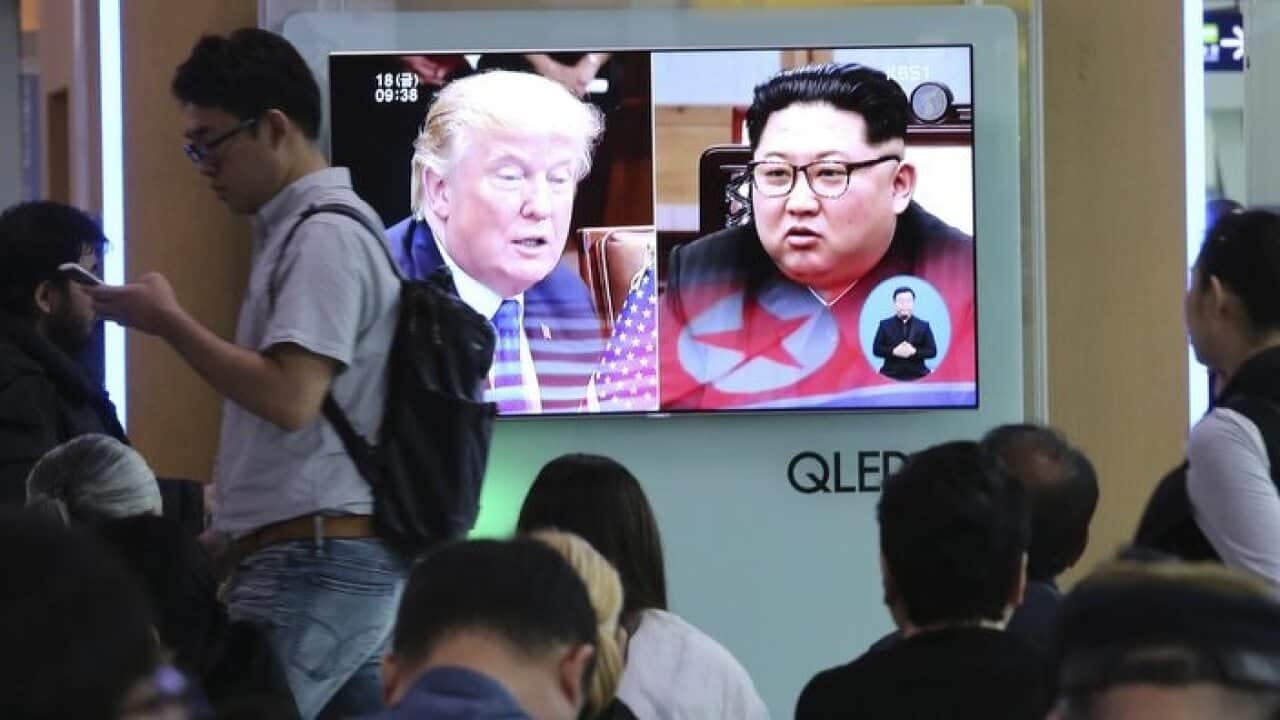 People watch a TV screen showing file footage of U.S. President Donald Trump, left, and North Korean leader Kim Jong Un during a news program.