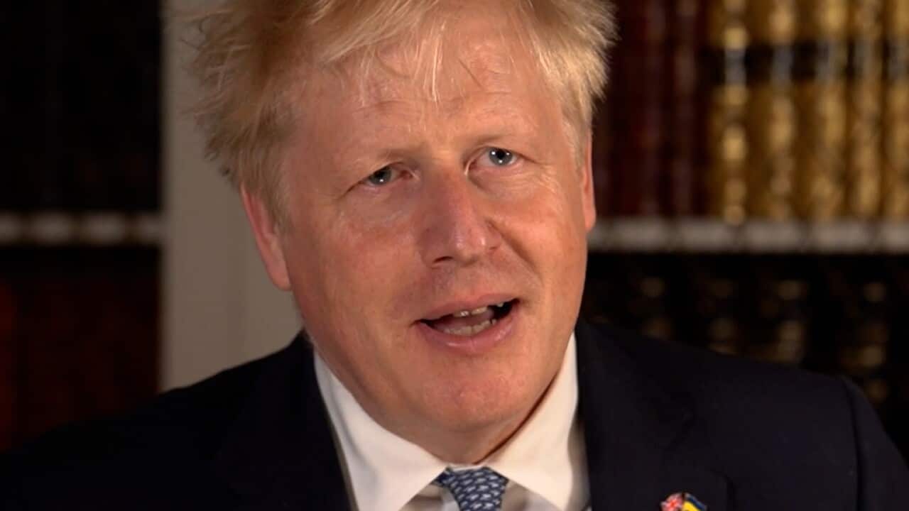 Boris Johnson sits down in a suit