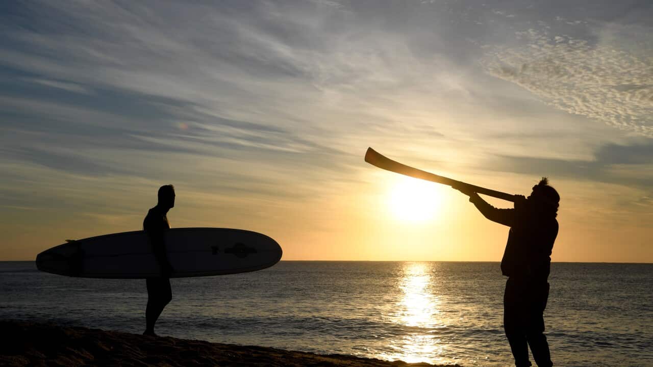 A surfer and an Indigenous didgeridoo player are seen as part of a protest at Bells Beach south of Melbourne