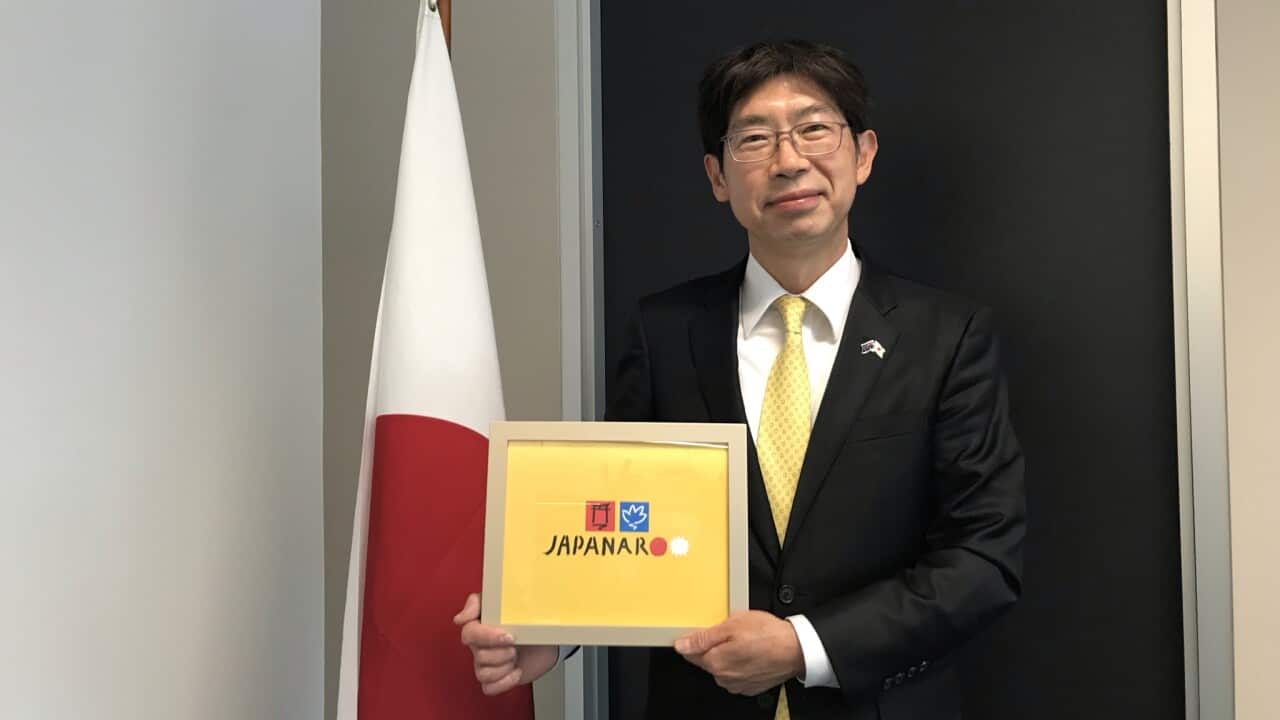 Kiya Masahiko, Consul-General of Japan in Sydney, holding the key visual by Australian artist Ken Done for a Japanese festival called Japanaroo