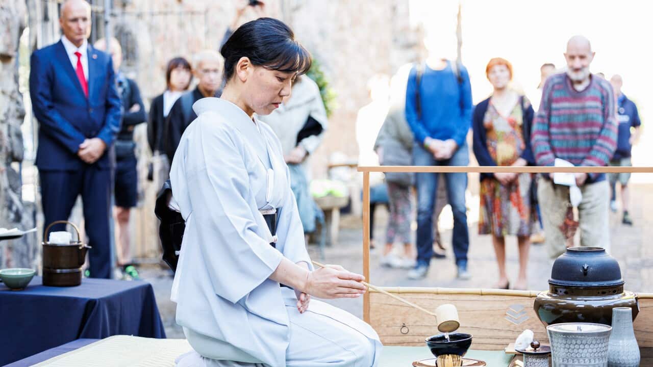 A woman kneels and pours tear at a ceremony to mark the bombing anniversary