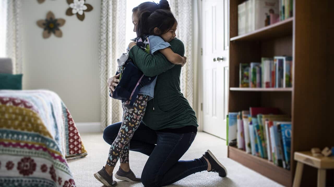 Mother embracing young daughter before school