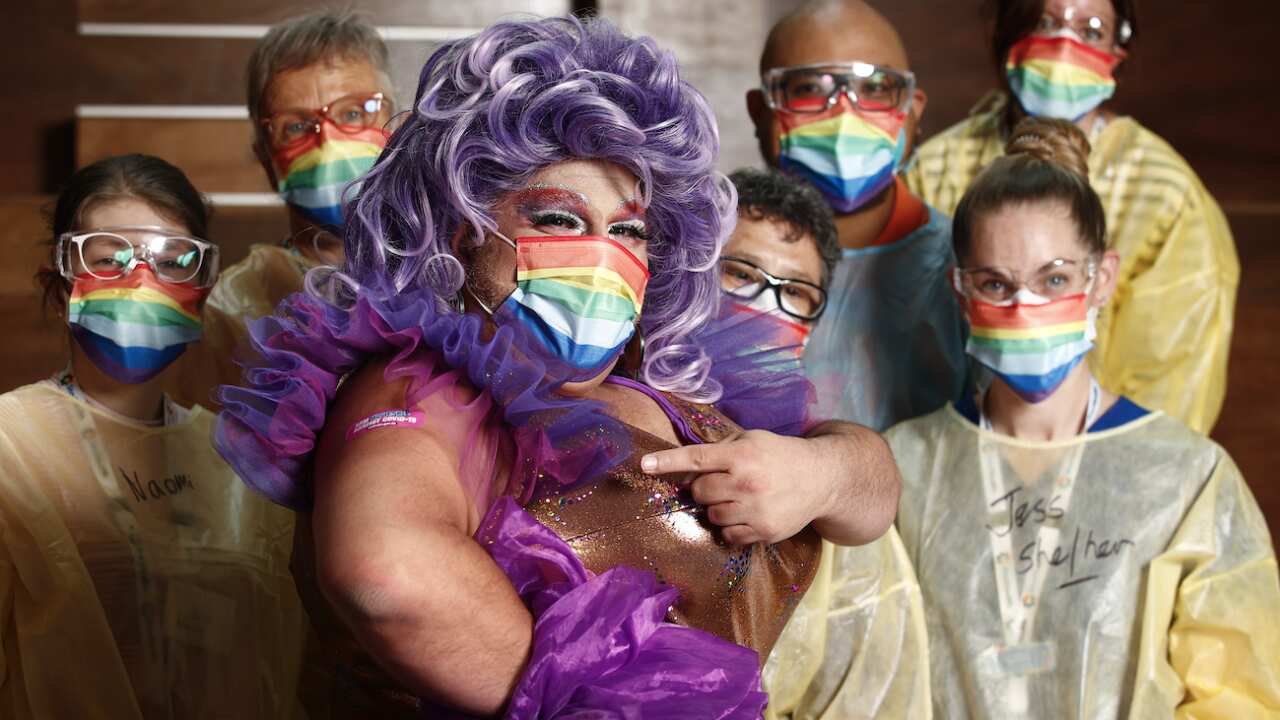 Frock Hudson (centre) poses for a photograph with health staff at the Victorian Pride Centre in Melbourne, Monday, October 18, 2021