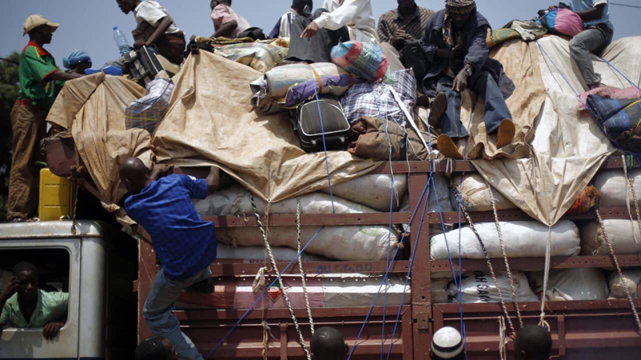 Men flee on the top of a truck out of the Central African Republic
