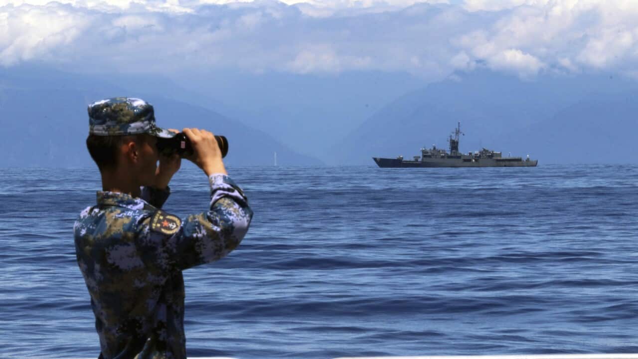 A People's Liberation Army member looks through binoculars from a ship during a military exercise