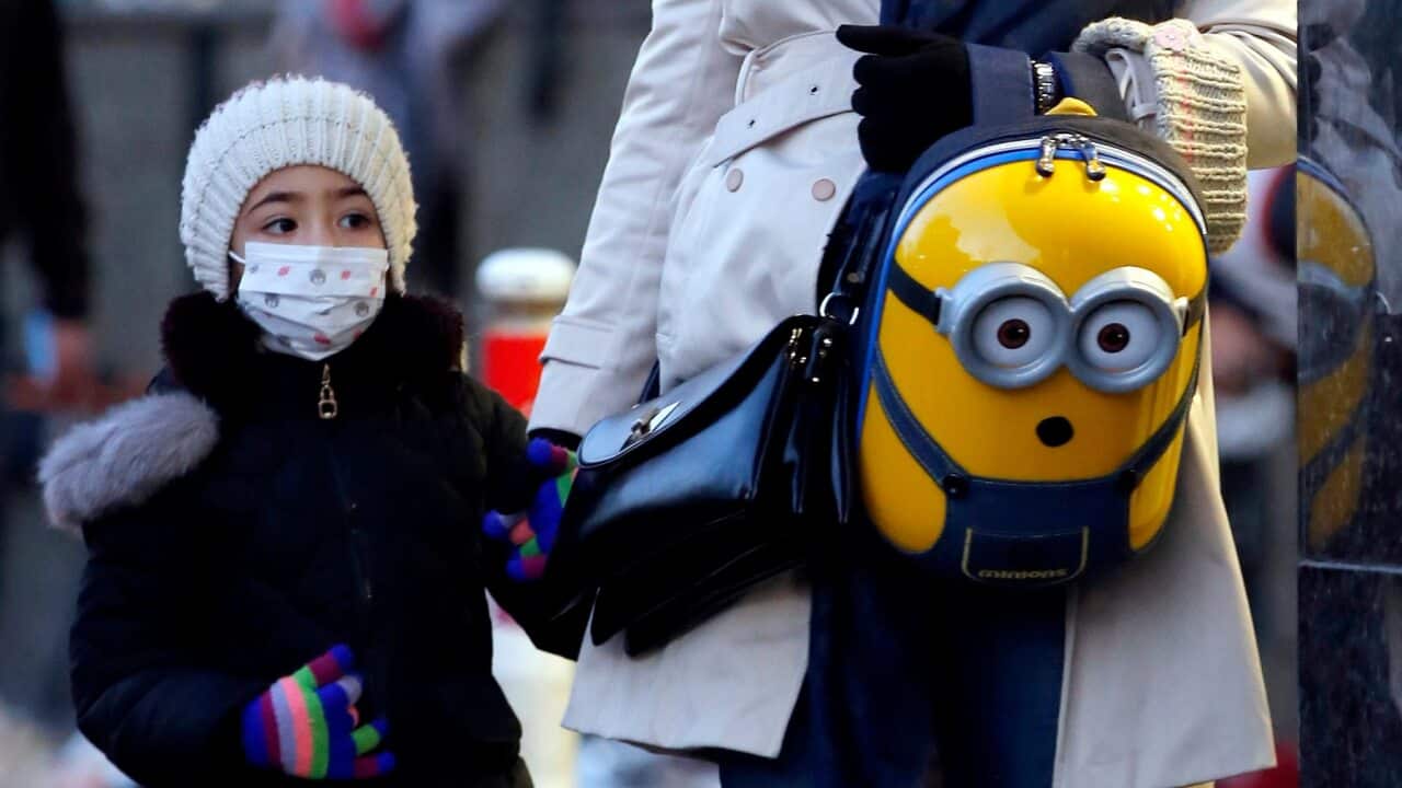 An Iranian woman and her child wearing face masks walk on a street of Tehran, Iran, 22 February 2020.