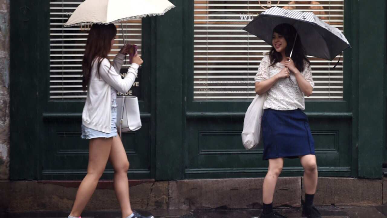 Pedestrians shelter from the rain in Sydney