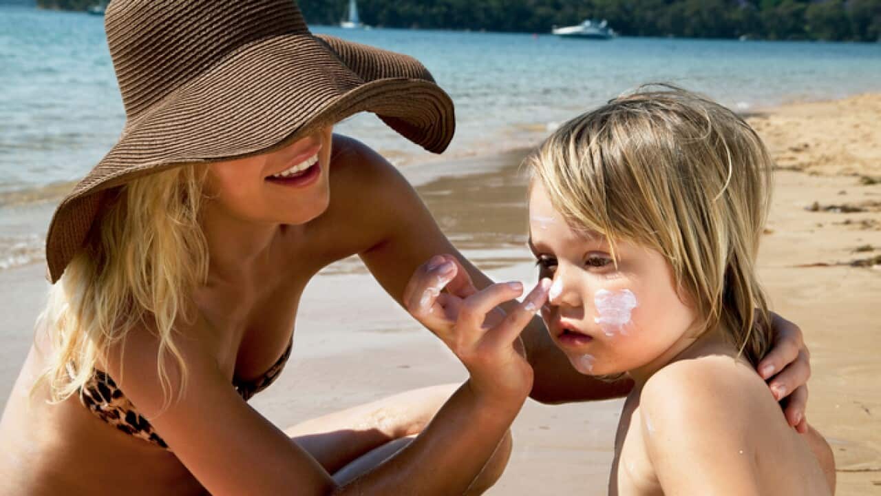 Mother putting sunscreen on her son at the beach