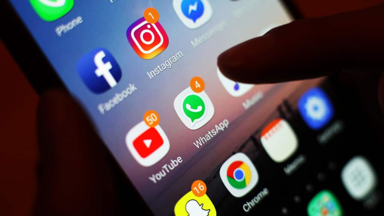 An image of a hand holding a phone, showing images of different apps