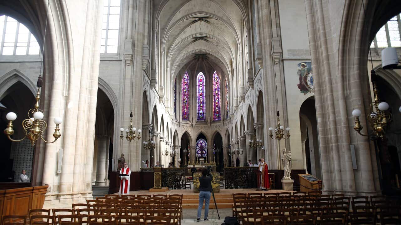 A priest carries the processional cross during the Way of the Cross ceremony at the Saint Germain l'Auxerrois church in Paris.