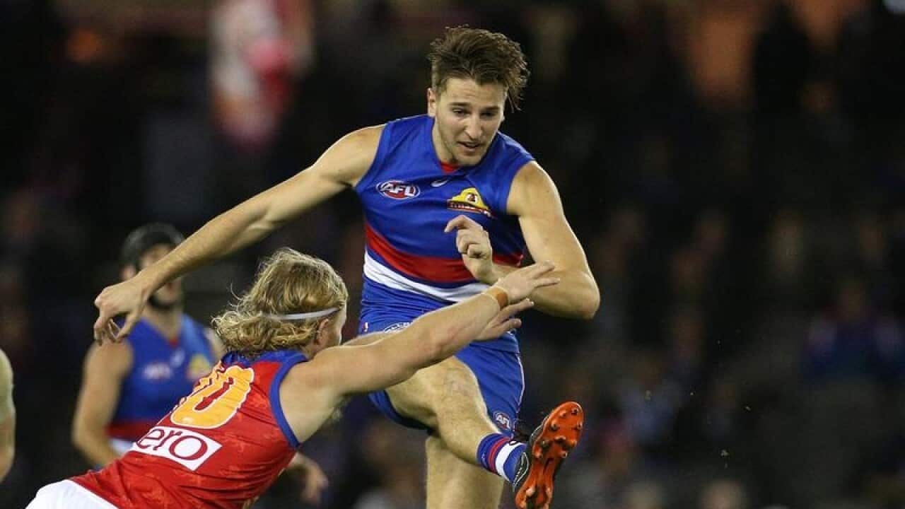 Marcus Bontempelli of the Bulldogs kicks under pressure.
