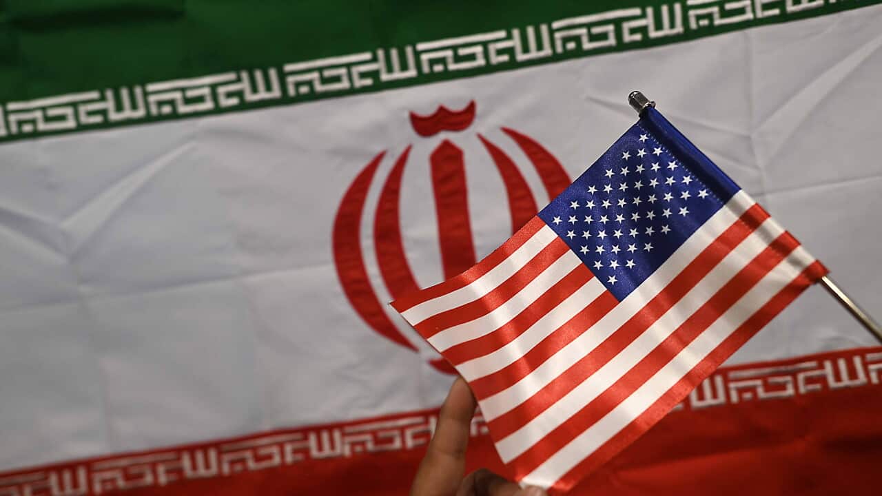 A US flag held in front of an Iranian flag.