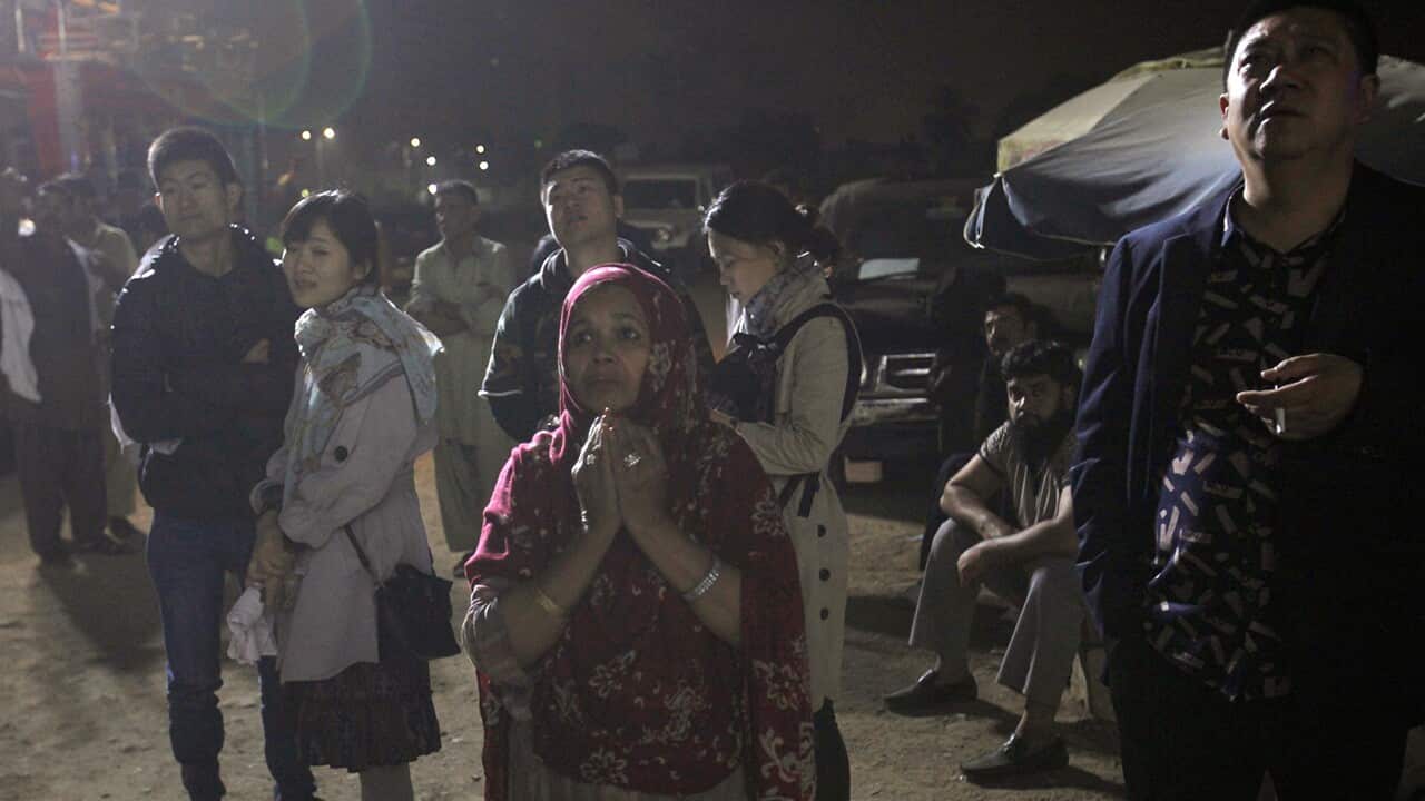 People stand outside a hotel on fire in Karachi
