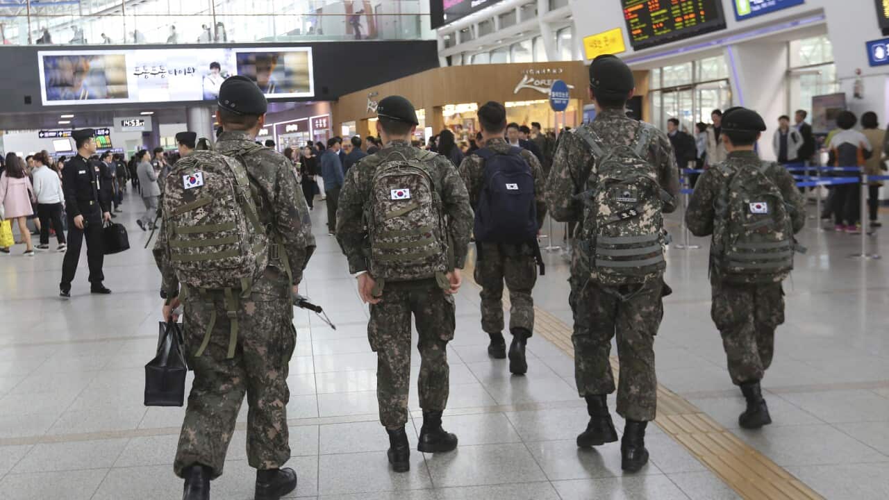 South Korean soldiers walking through airport terminal.