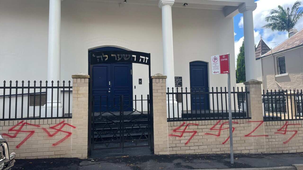 The fence of a synagogue with the red Nazi Hakenkreuz symbol painted in red multiple times.