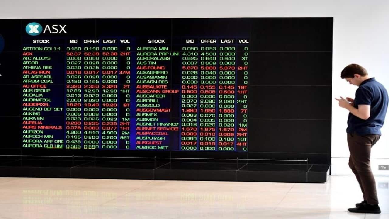 Man looking at mobile phone near ASX Board