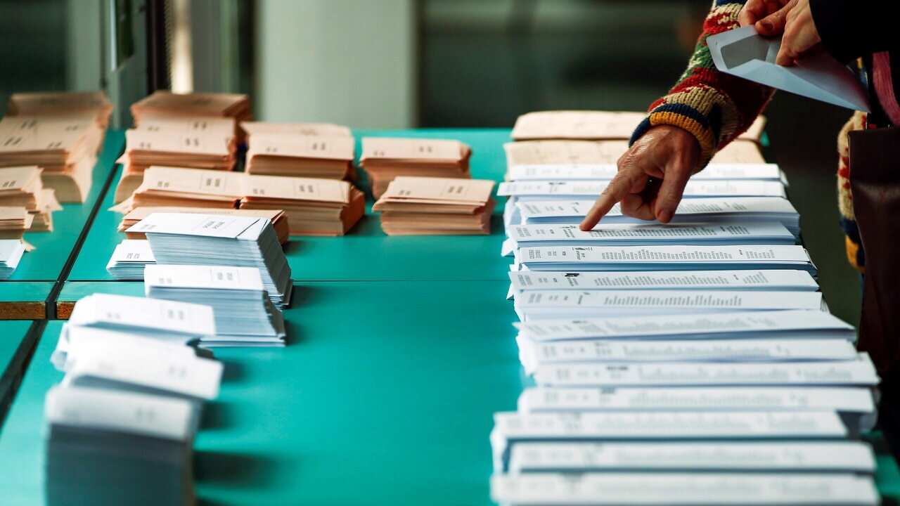 A woman picks a ballot paper during general elections at a polling station in Barcelona.