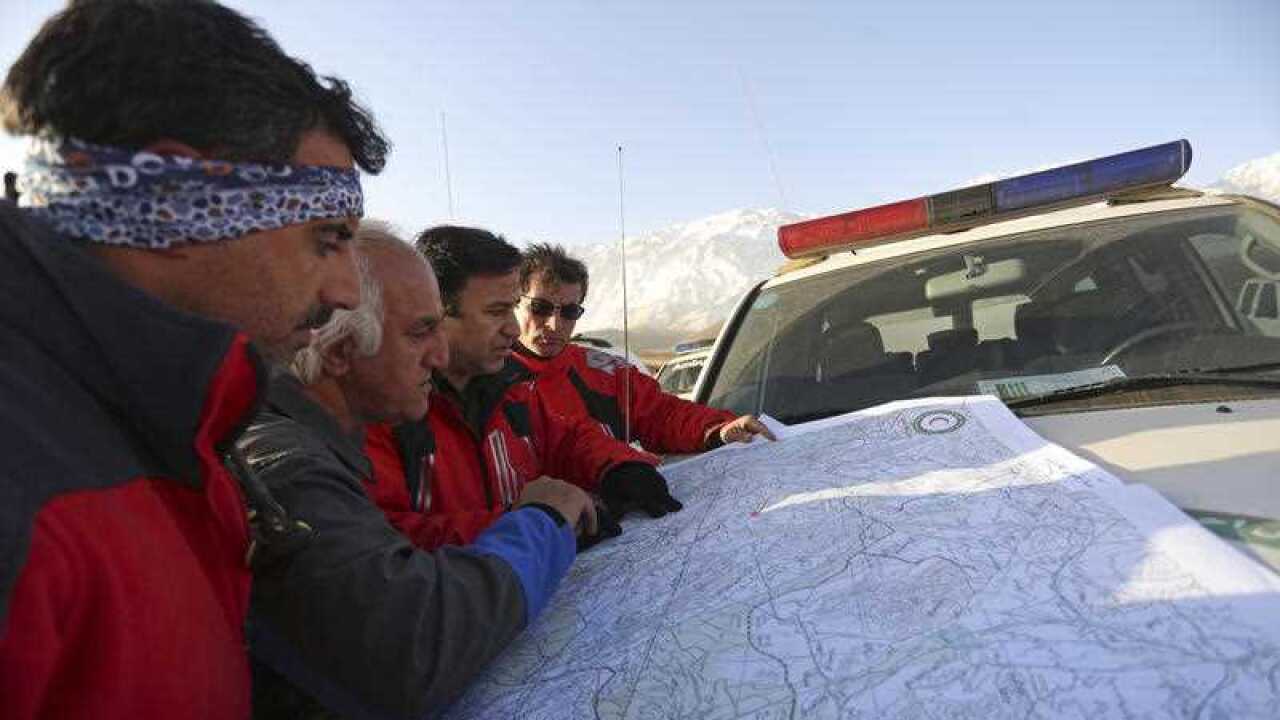 Members of the rescue and search team look at a map of the area where a plane crashed on Mount Dena, in southern Iran.