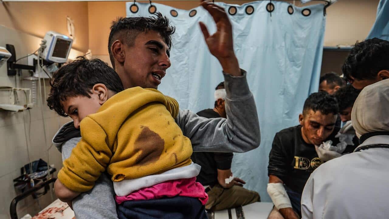 A young man holding a toddler inside a hospital