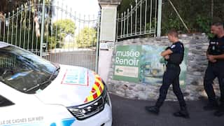 Two police officers standing outside of the Renoir Museum which is gated.