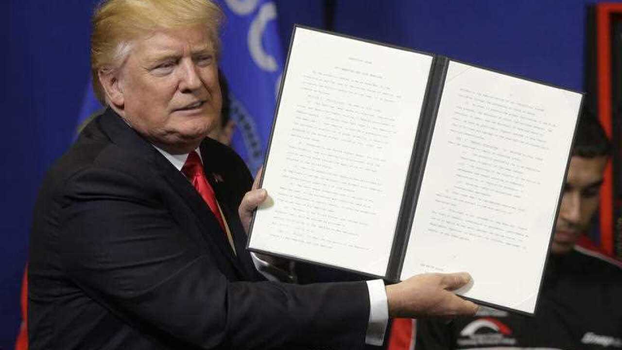 President Donald Trump holds up an executive order to tighten the rules for technology companies seeking to bring highly skilled foreign workers to the US